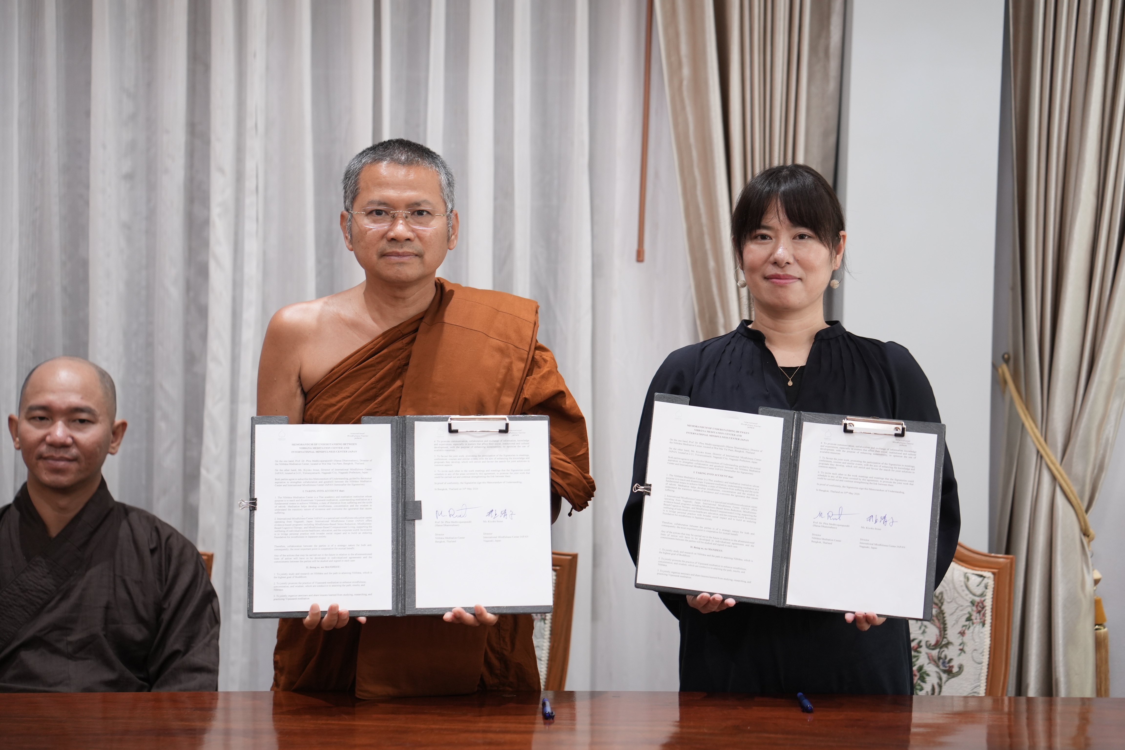 Ms. Kiyoko Inoue and Ven. Prof. Dr. Medivajarapundit (Hansa Dhammahaso) holding signed MOU documents.