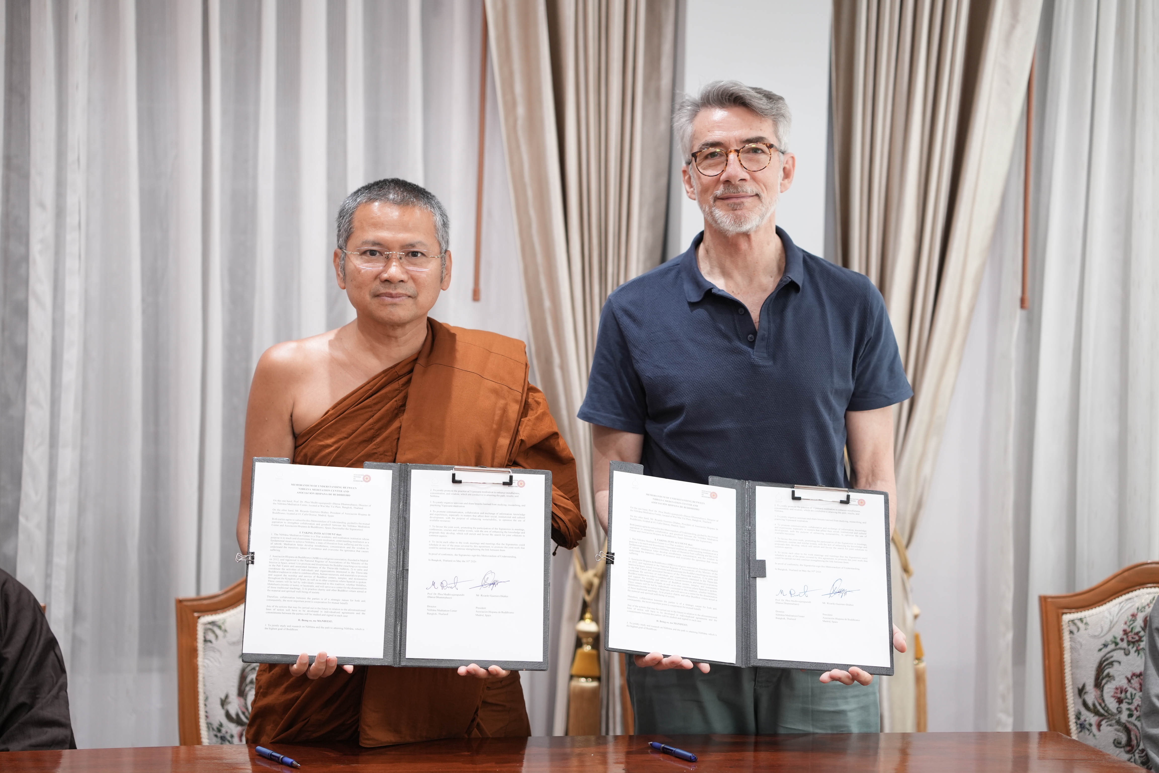 Mr. Ricardo Guerrero and Ven. Prof. Dr. Medivajarapundit (Hansa Dhammahaso) holding signed MOU documents.